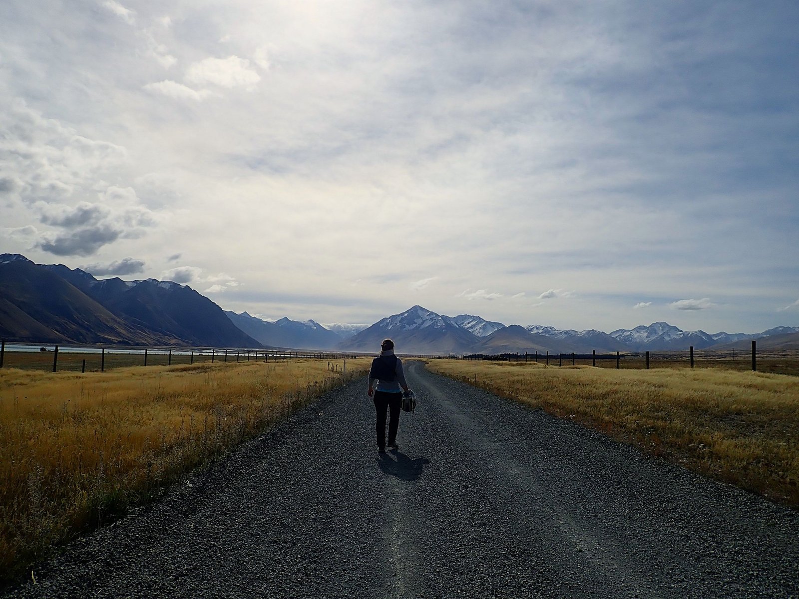 Lone person walking on gravel road wide landscape